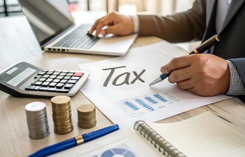 man-is-writing-paper-with-pen-calculator-it